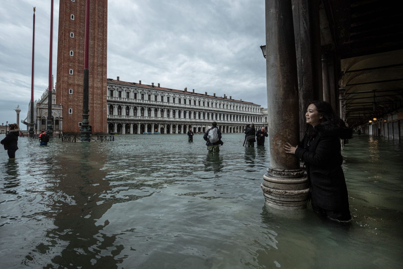 A woman looks on towards Sanint Mark's Basilica in Saint Mark's Square during the high tide, November 15, Venice, Italy. Entrance to the iconic square has been forbidden for safety concerns and the area is patroled by police officers. Record 187 cm high tide hit Venice on Nov. 12, creating damages to the historical and cultural heritage.
